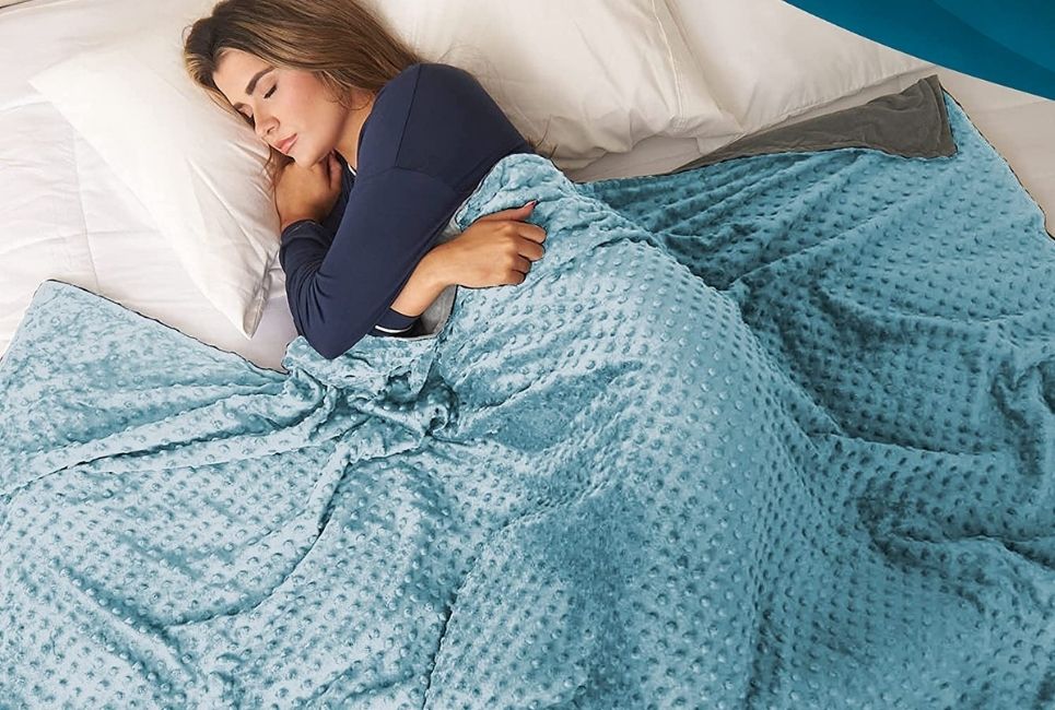 woman sleeping peacefully under light blue weighted blanket