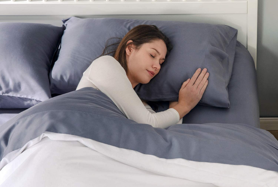 woman sleeping peacefully on dark grey sheets in bed
