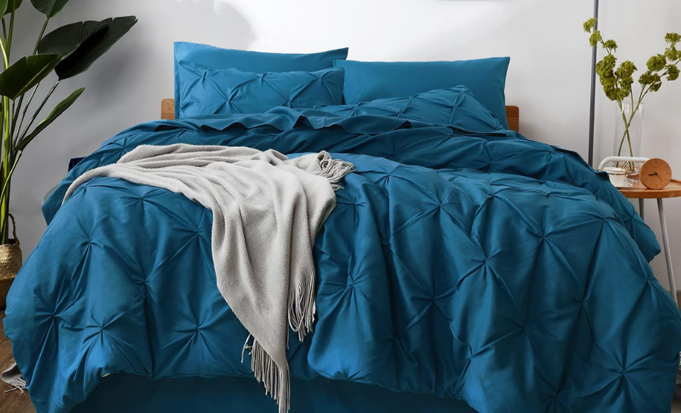 messy bed with pinch pleat teal comforter and pillows