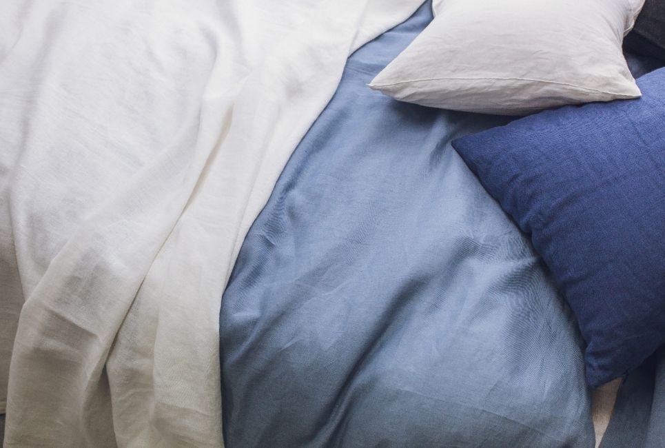 Close up of blue sheets on bed with cotton pillows