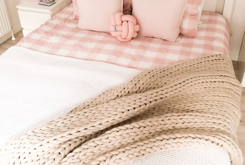 pink checkered bedding with knitted blanket and throw pillows