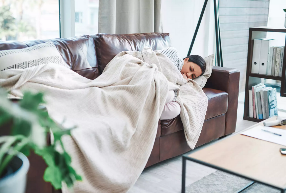woman sleeping on couch in trendy room with blanket over her