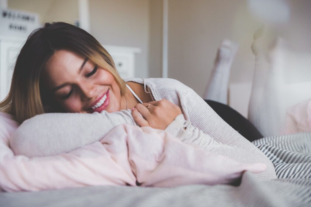 woman smiling laying down on bed with soft microfiber blanket