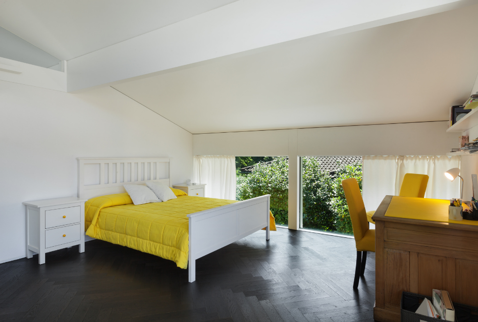 yellow comforter on neatly made bed with desk in room