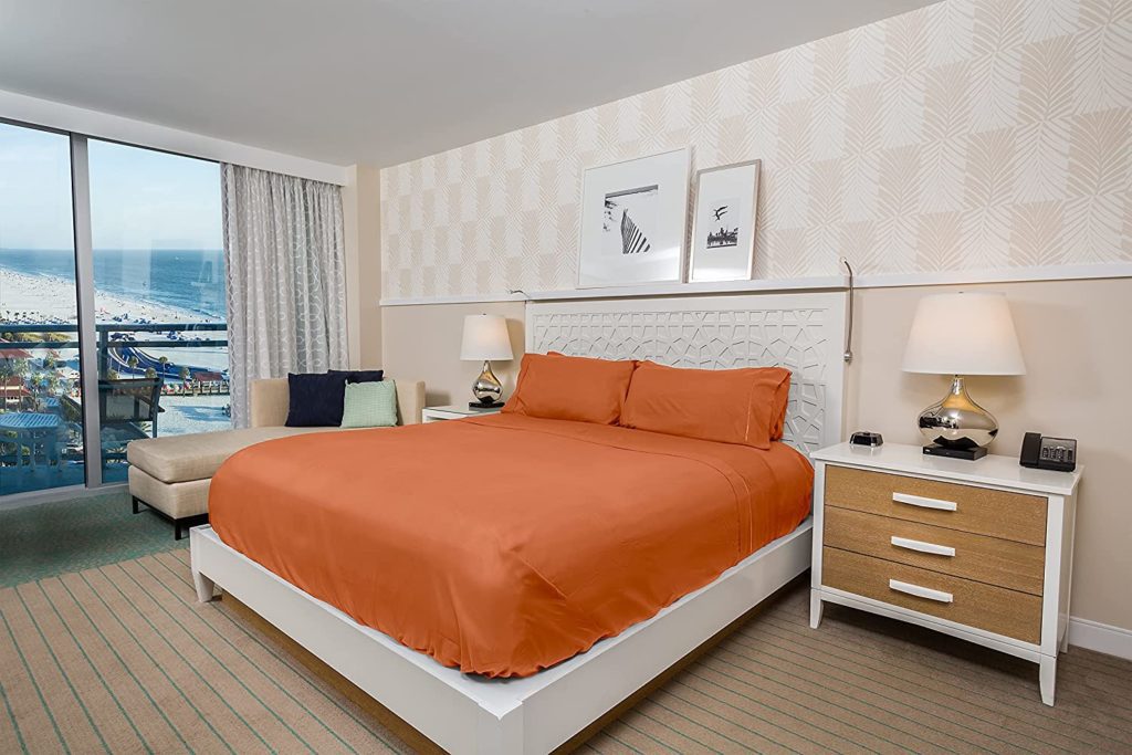 hotel room overlooking beach with orange sheets on bed