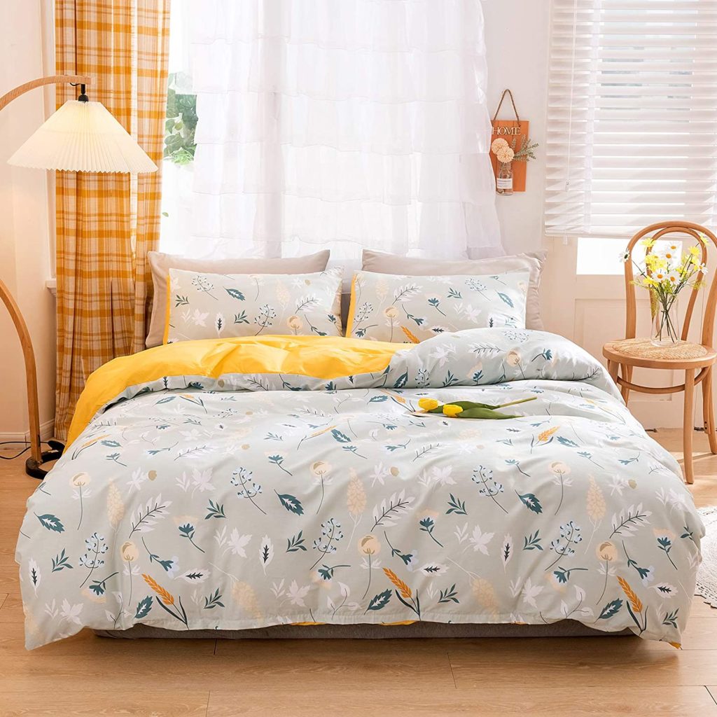 Grey and pastel colored floral comforter with yellow backing on bed