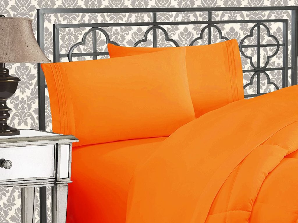 bed made with orange sheets and comforter in elegant room