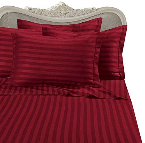 Red striped bedding close up with pillows and ornate headboard