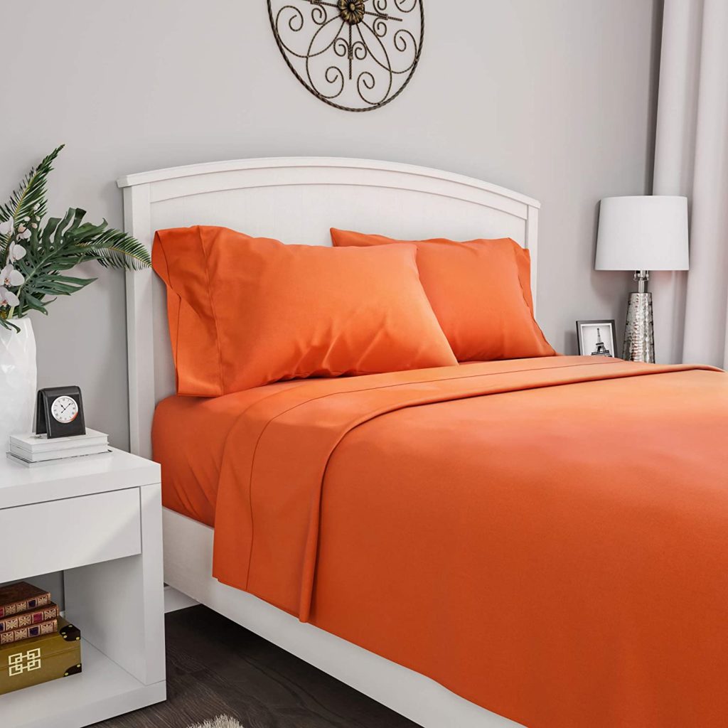 neatly made bed in traditional room with orange sheets