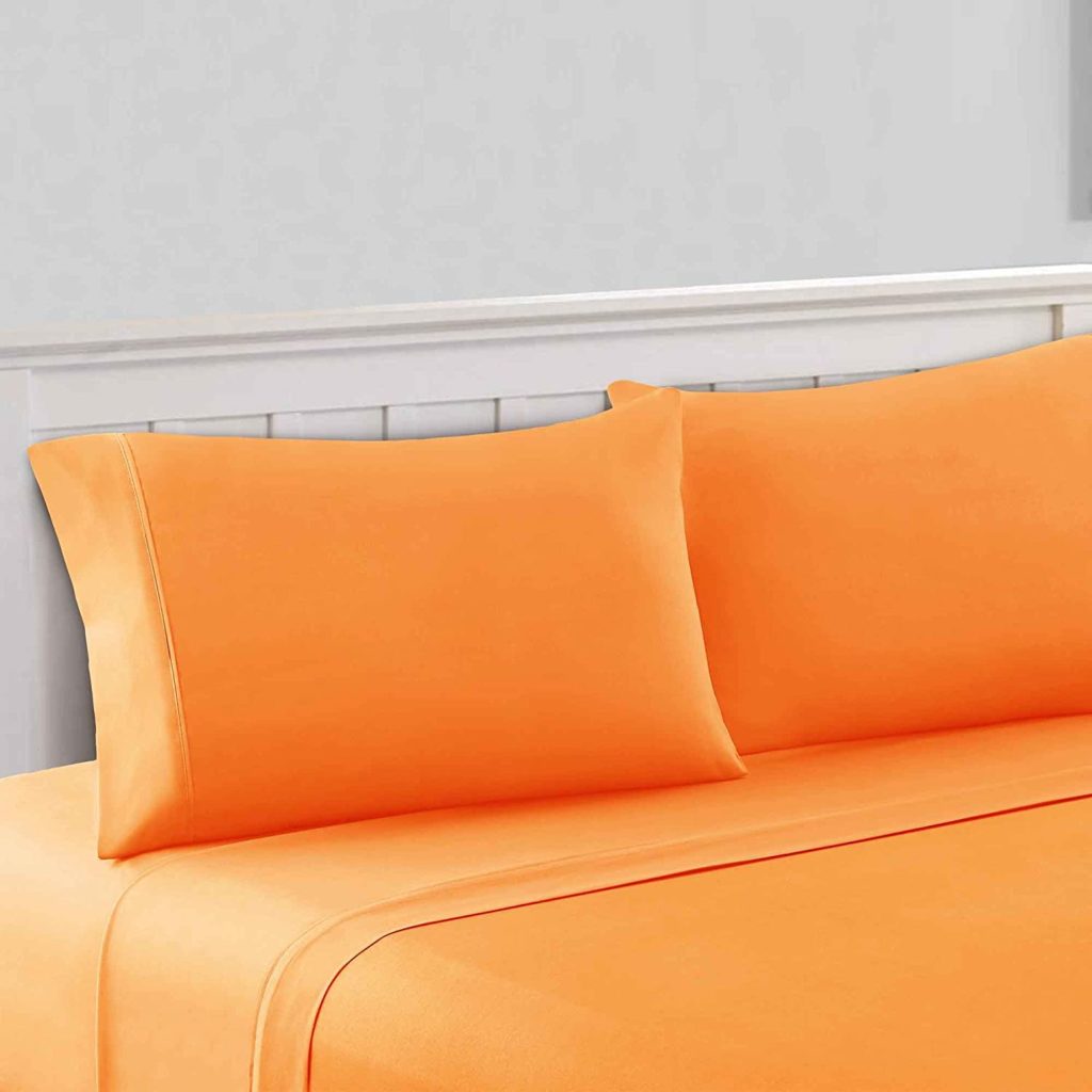 pillows on bed with orange pillowcases and sheets