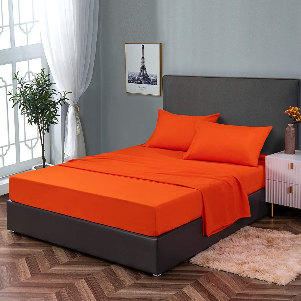 bright orange sheets on neatly made black upholstery bed