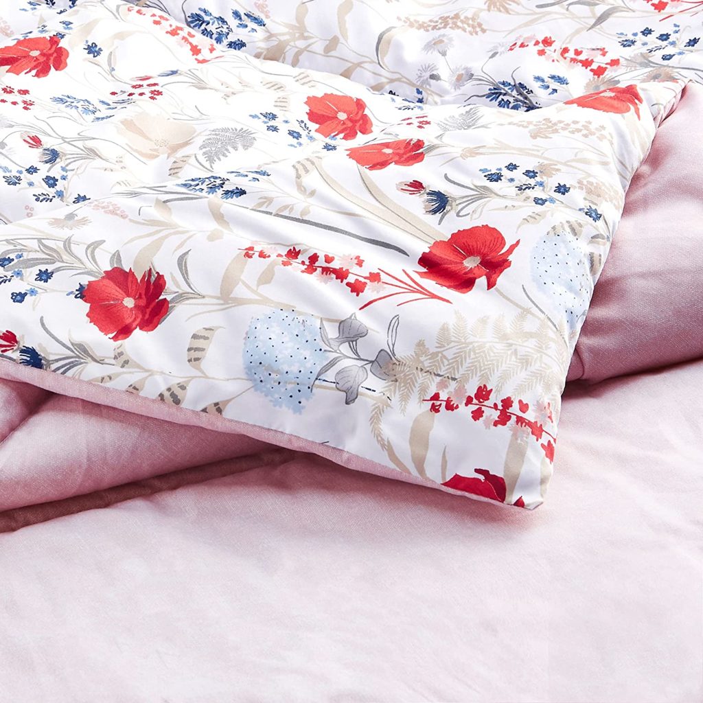 Corner of reversible pink and floral comforter folded over 