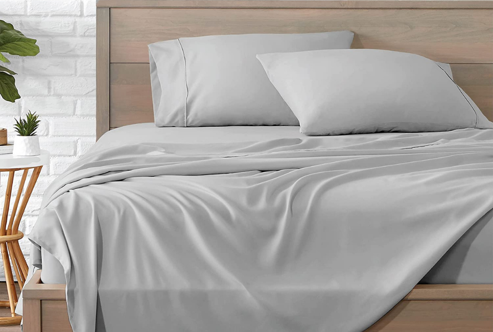 grey sheets on unmade bed in cozy clean room