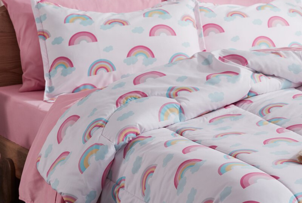 close up of comforter with rainbows and clouds print and pink sheets