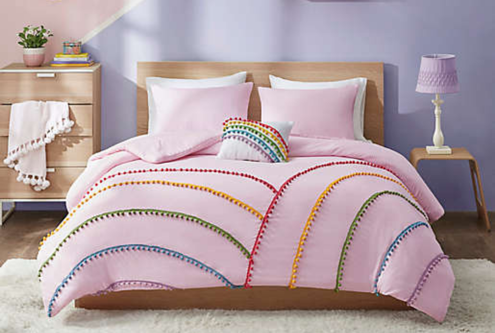 pink bedding on bed with rainbow pom pom details