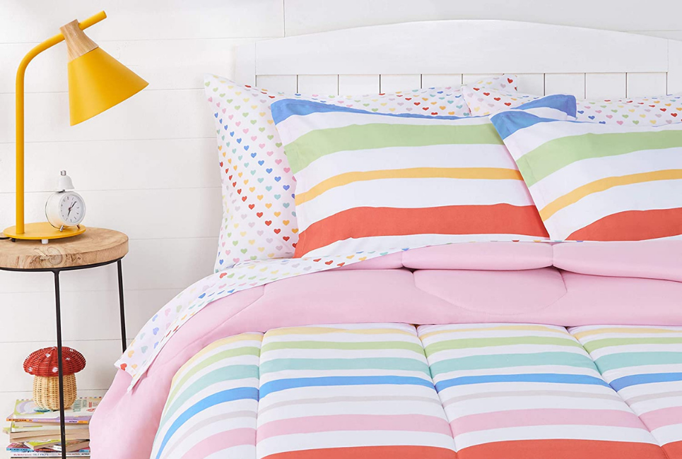 raindbow striped comforter on bed with multicolored heart print sheets