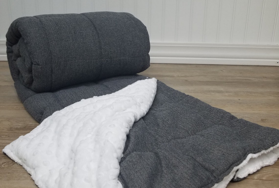 partiallly unrolled grey and plush white reversible blanket on hardwood floor