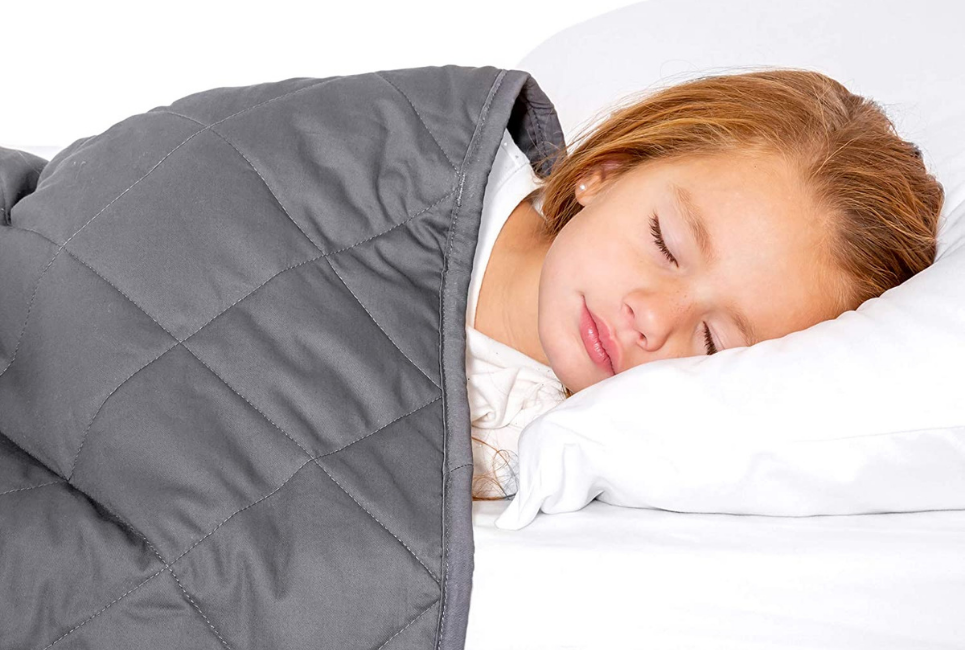 young girl sleeping peacefully under grey blanket