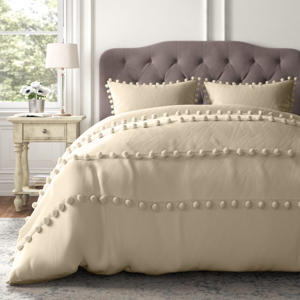 Beige Comforter set on bed with pom pom details