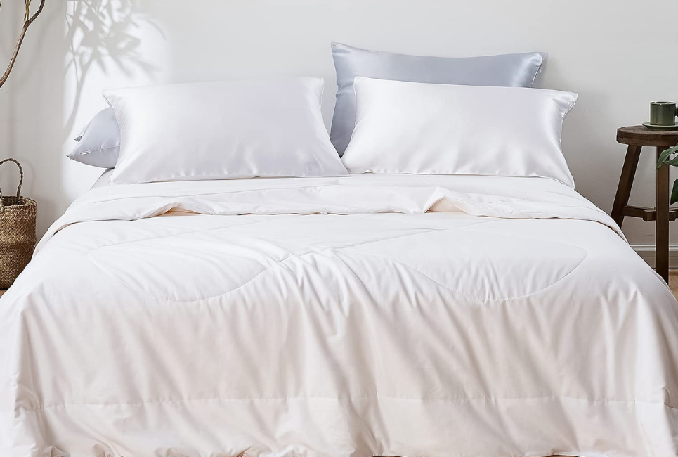bed made neatly with white silk bedding