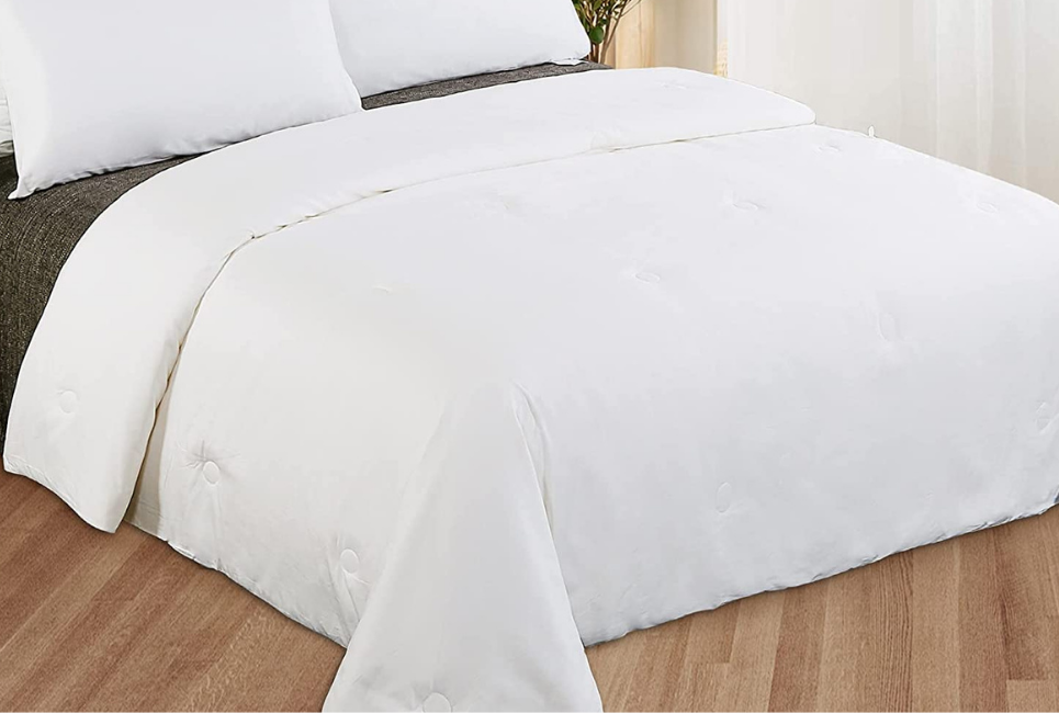 bed made neatly with white silk comforter
