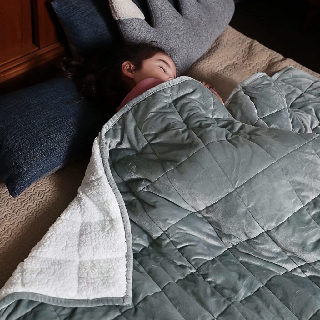 child sleeping under reversible grey weighted blanket
