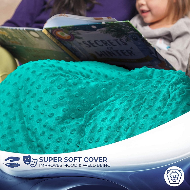 close up of child reading book with weighted blanket over lap