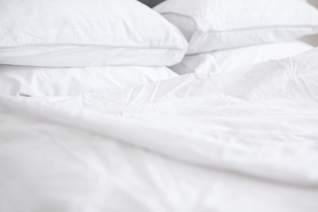 close up of slightly wrinkled white sheets on bed