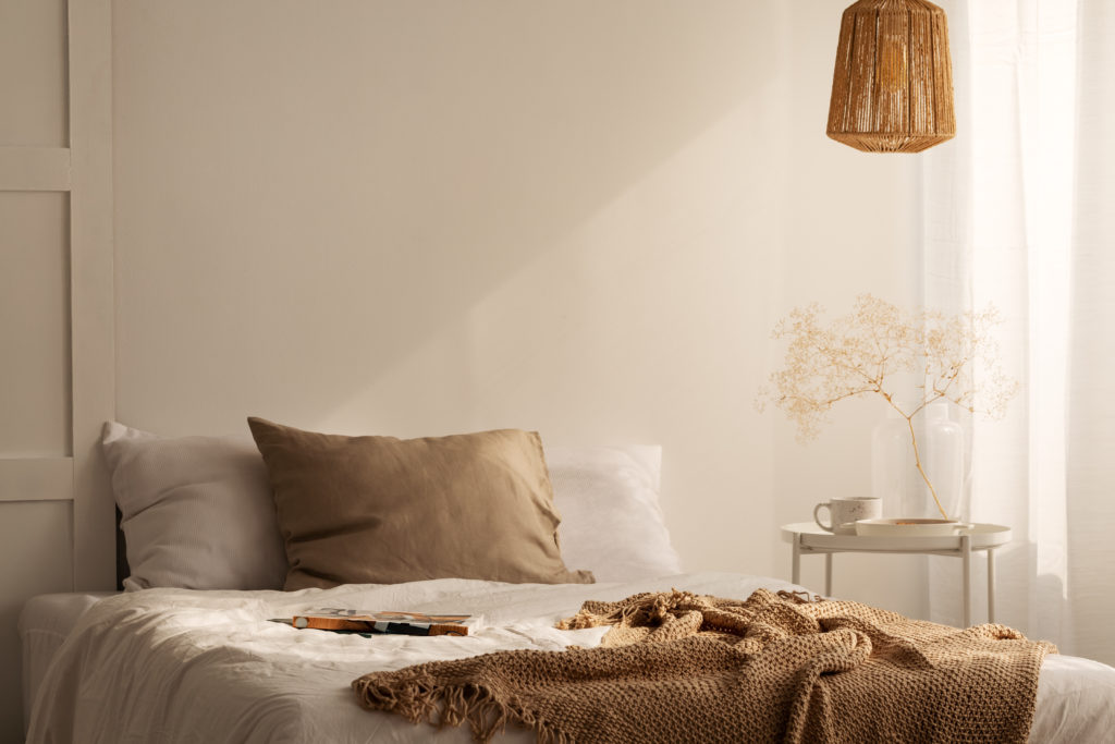 closeup of bed with beige blanket and linen pillow
