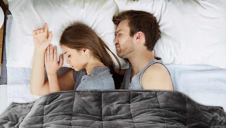 couple sleeping in bed under weighted blanket