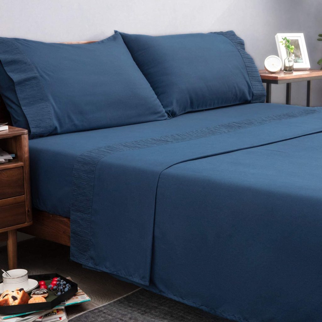 dark blue sheets on bed in moody room
