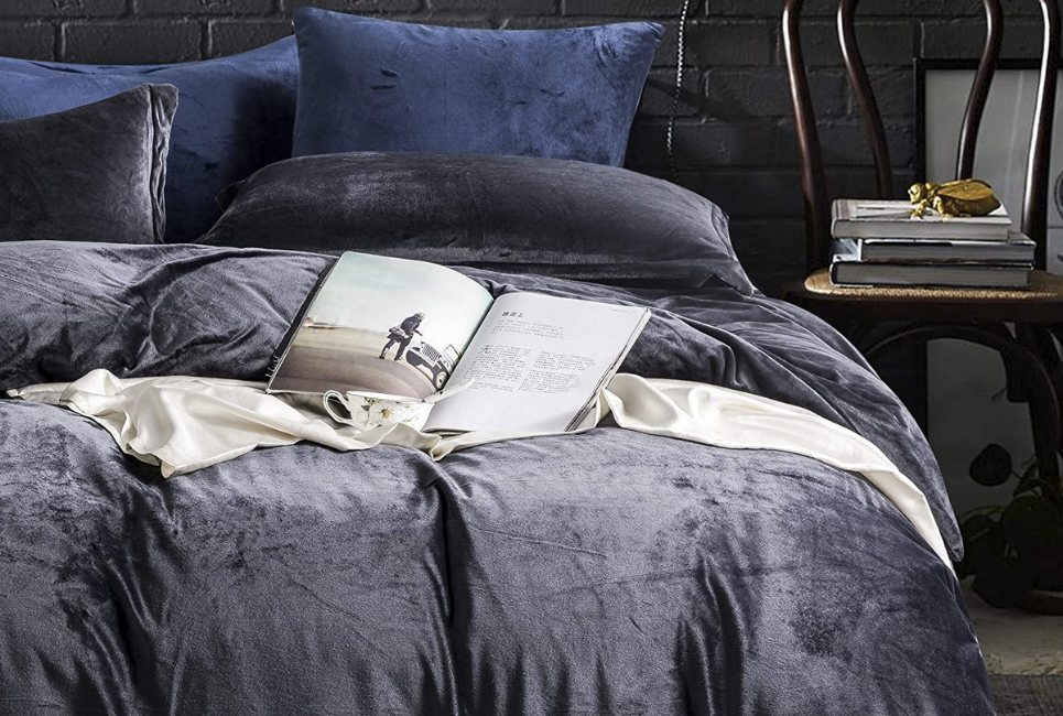 dark blue velvet comforter with open book on unmade bed
