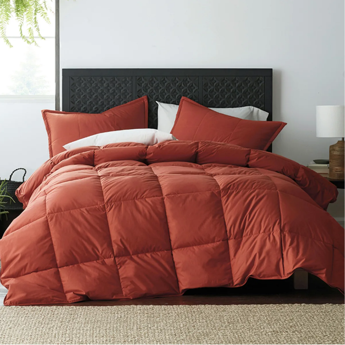 dark orange comforter on unmade bed