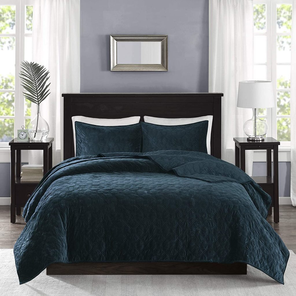 dark teal comforter on bed in modern room