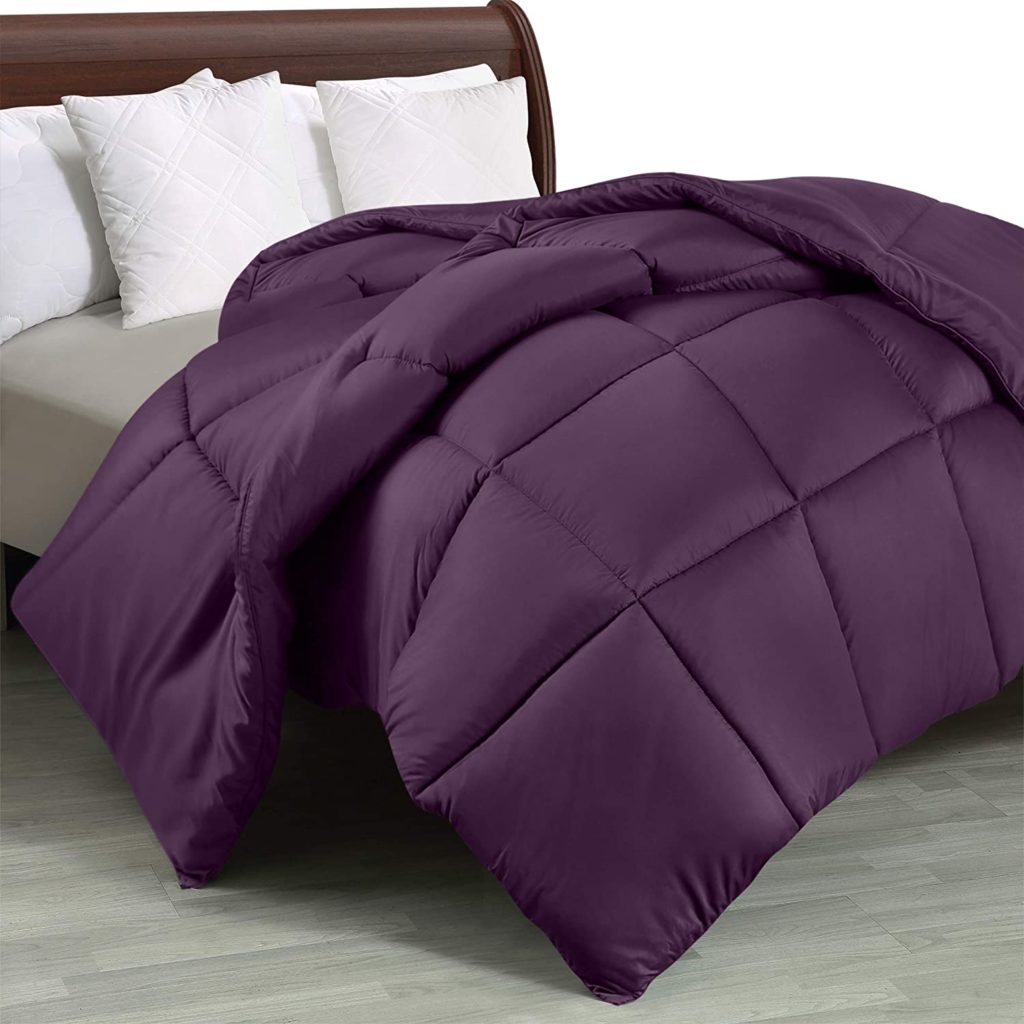 deep purple comforter hanging off bed