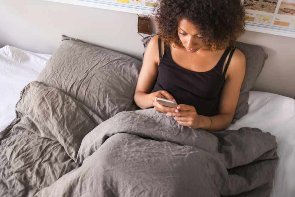 woman relaxing sitting in bed on phone
