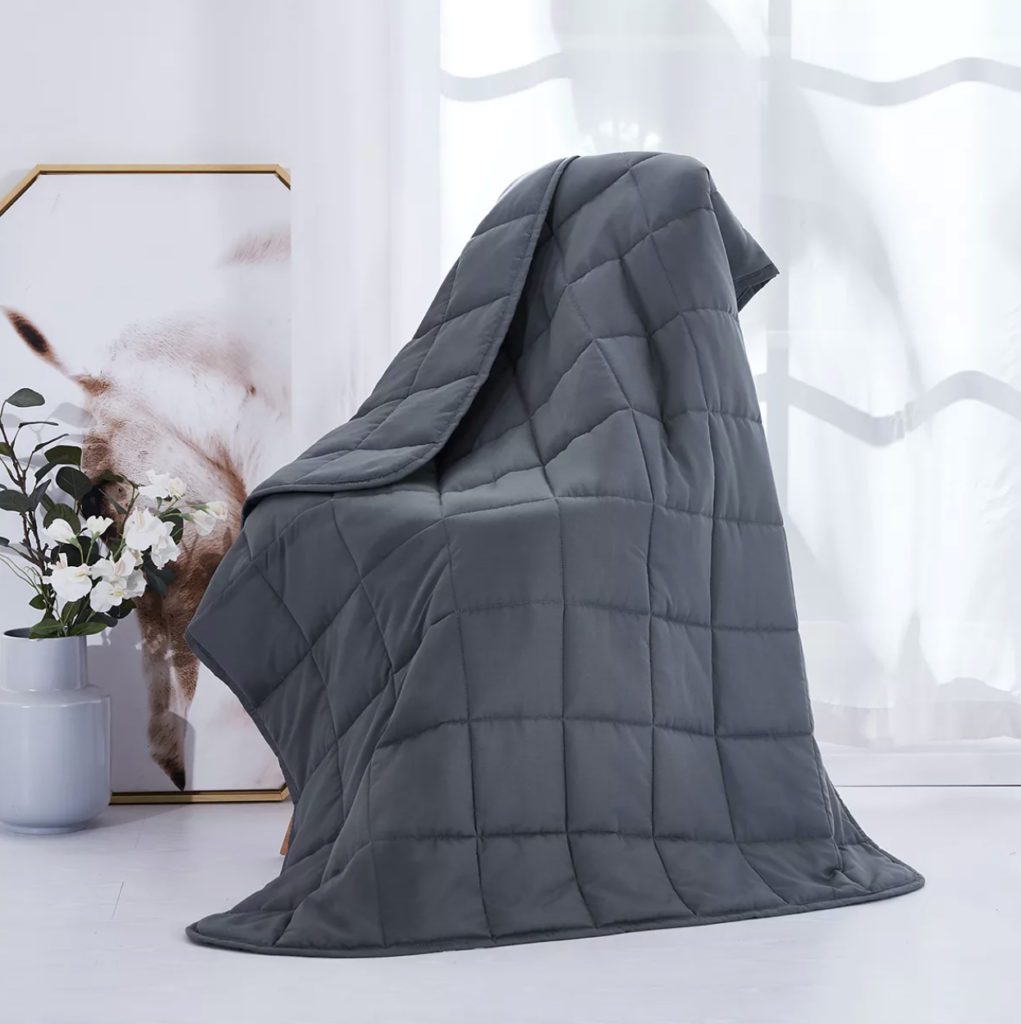 grey weighted blanket draped in modern room with art and decor