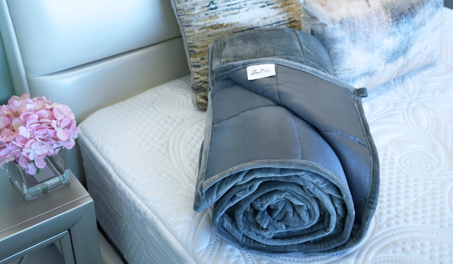 grey weighted blanket rolled neatly on a bed