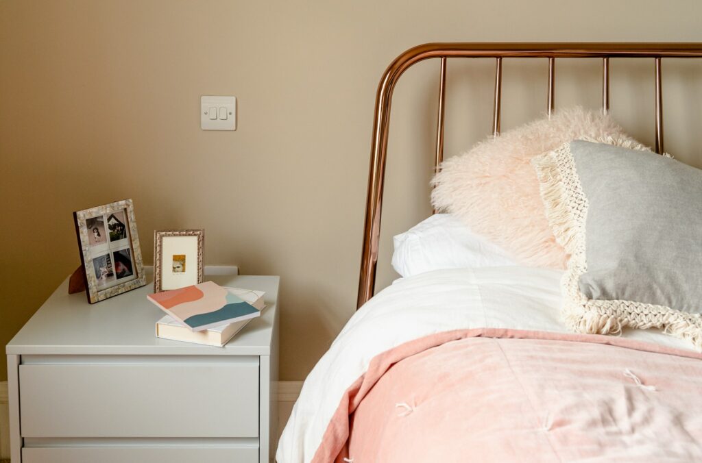 rose gold headboard with pink bedding and tidy nightstand