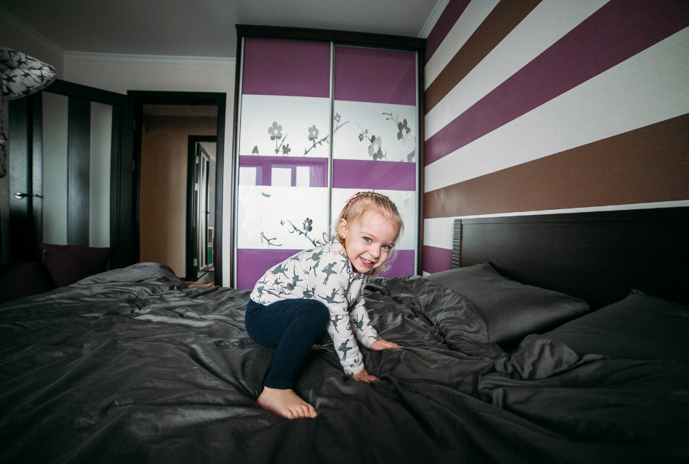 little girl playing on bed with black sheets