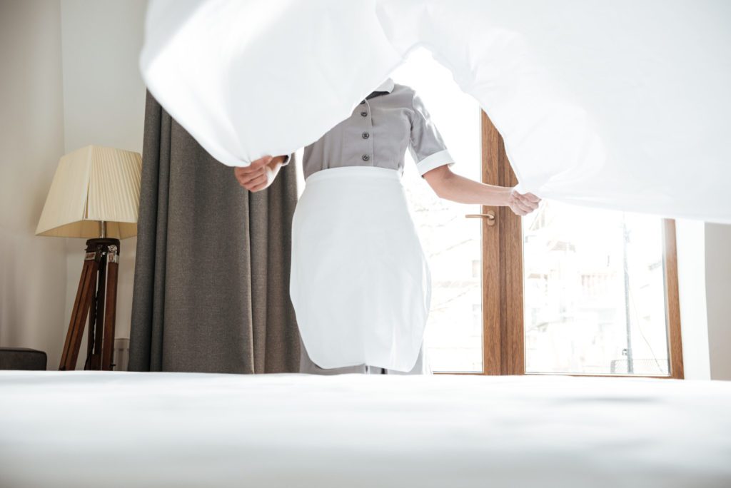 maid making bed with white sheet