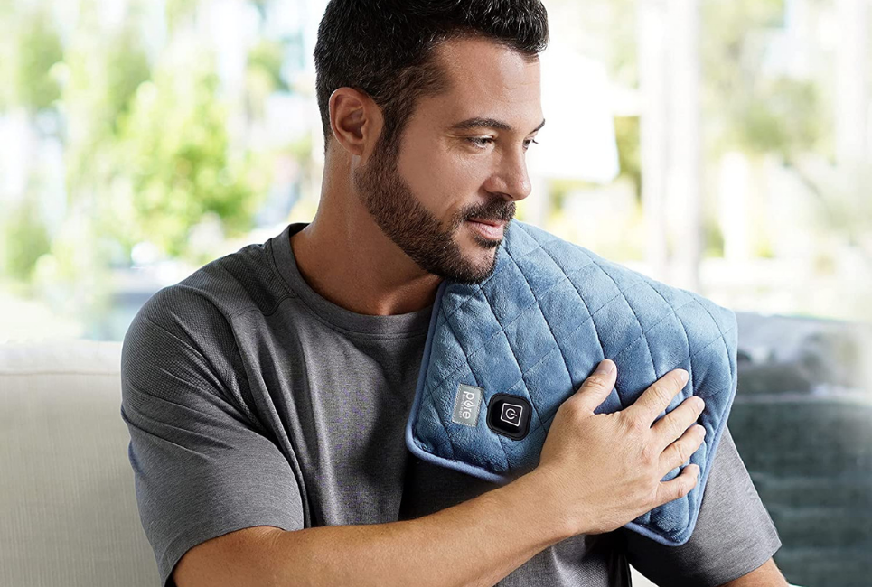 man holding a heated quilted pad on his shoulder