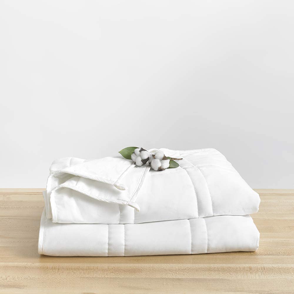 neatly folded white blanket with cotton plant on top