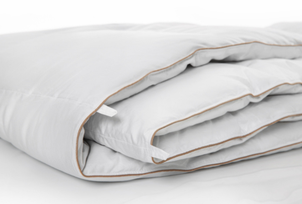 neatly folded white comforter with brown piping