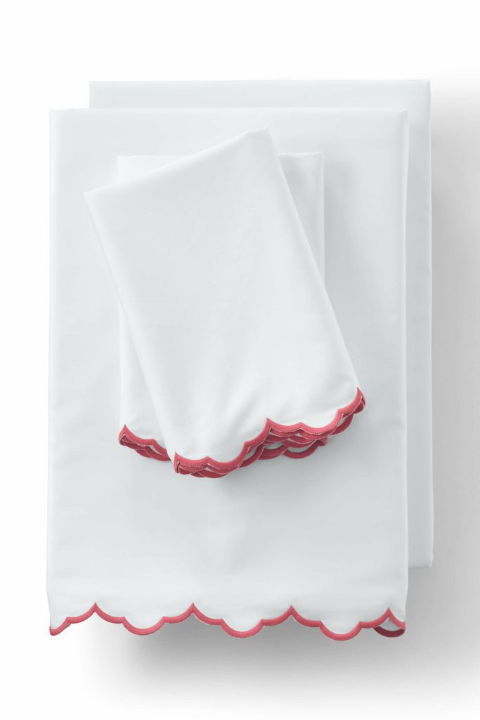 neatly folded white sheets with red scalloped trim