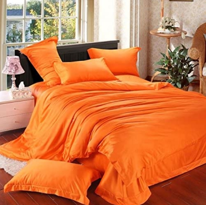 orange comforter on unmade messy bed