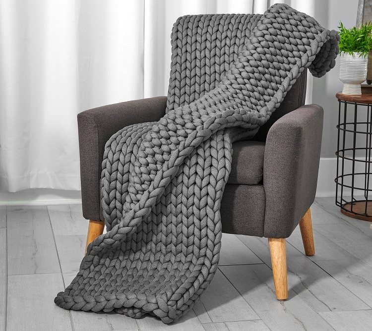 oversized knitted grey weighted blanket draped over chair