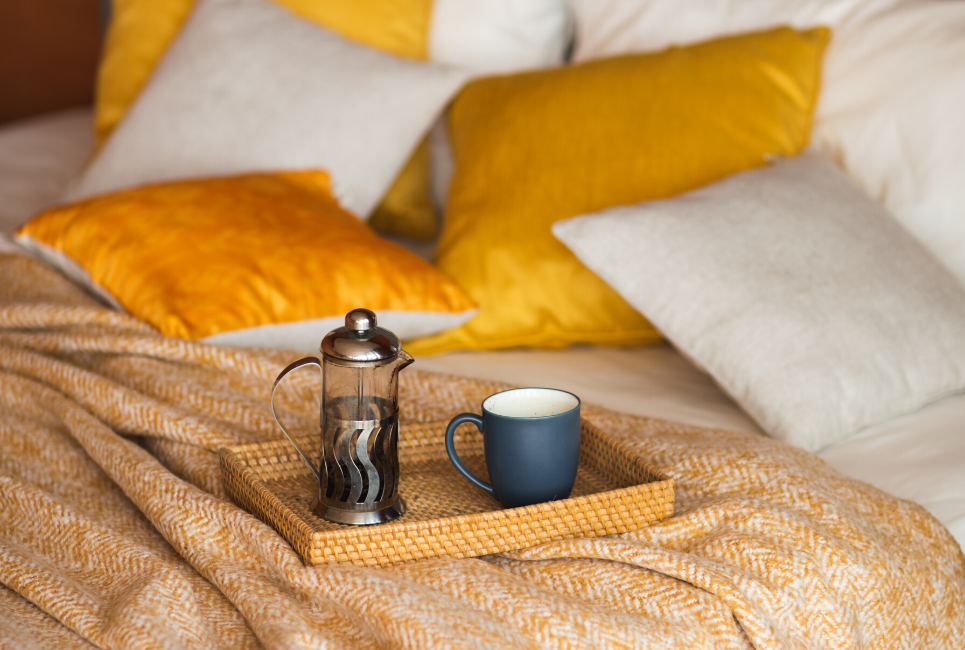 patterned white and orange comforter with coffee tray on bed