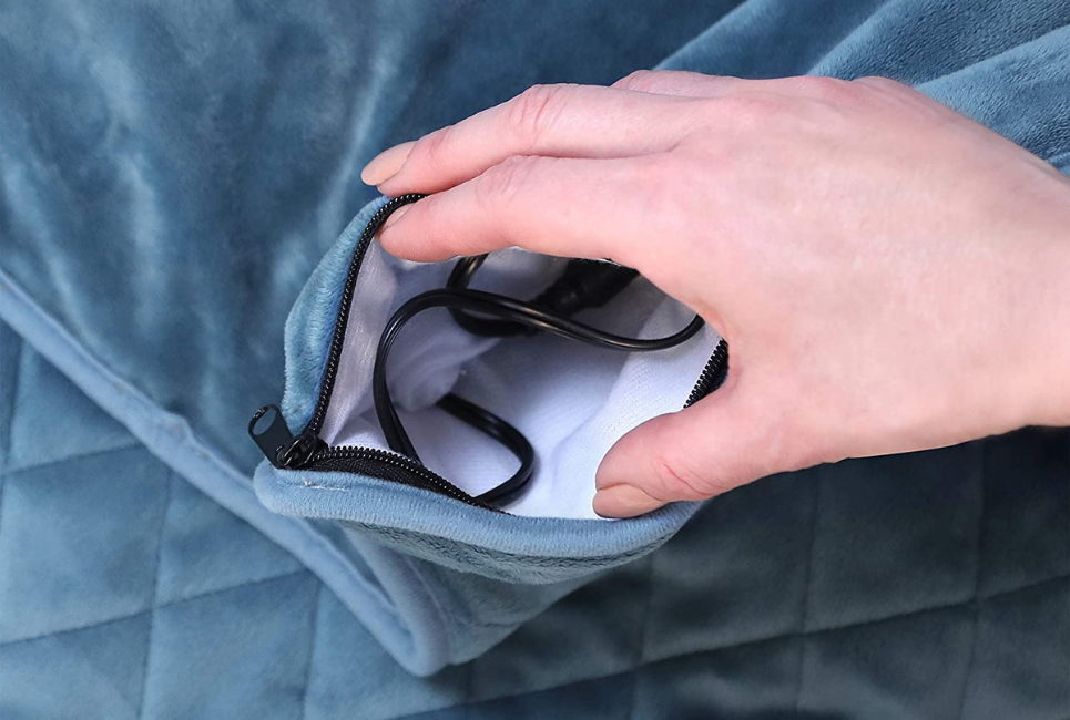 persons hand holding open the zipper on an electric blanket to expose heating cords