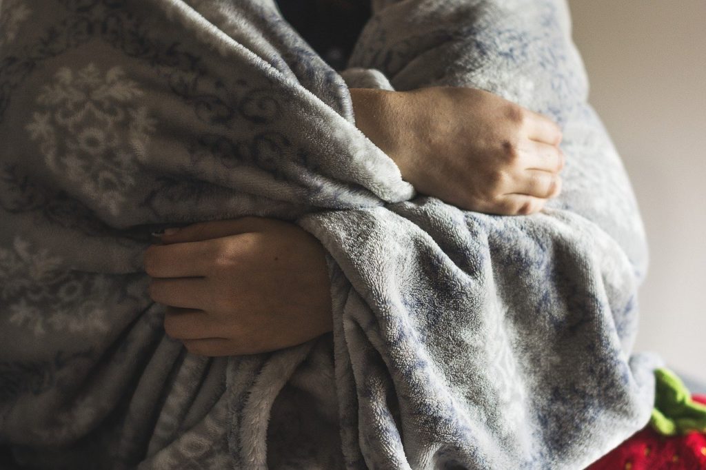 persons hands wrapped a weighted blanket around them